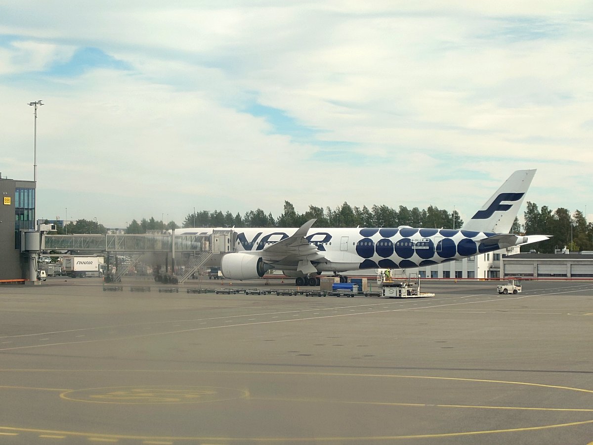 ヘルシンキ・ヴァンター国際空港のターミナルビル、オレンジのガードレール、青いバスとグランドサポート車両