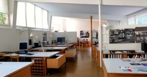 製図机と壁一面の白黒写真が並ぶスタジオ・アアルトの作業スペース